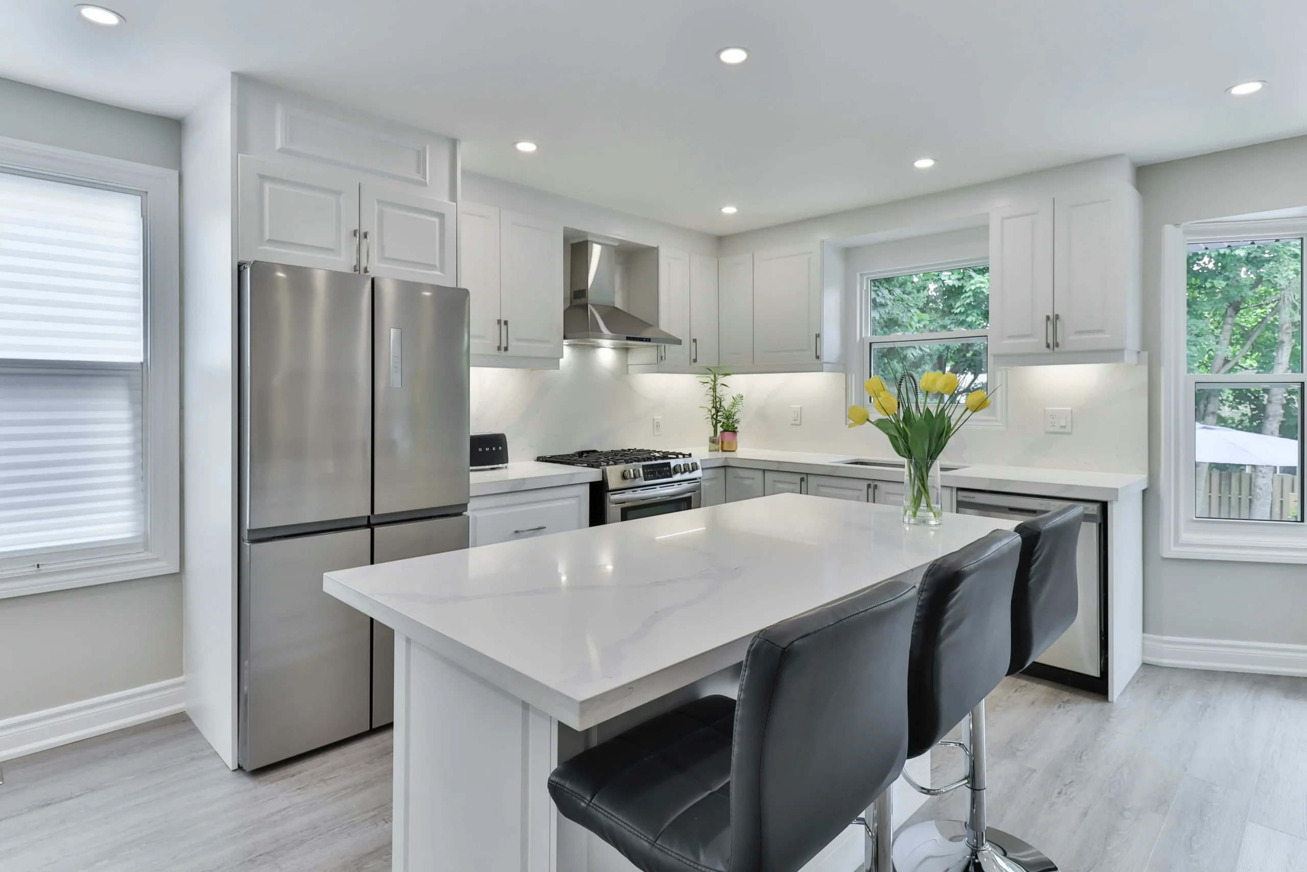 Modern kitchen showcasing Stonex’s Curated Collection, featuring elegant white quartz countertops, sleek cabinetry, and premium stainless steel appliances in a bright, open space with natural light and fresh floral decor.